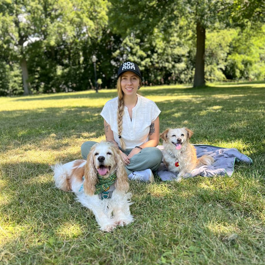 Dr. Nieto sitting in a sunny park with her two dogs.